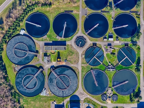 Aerial view of circular water treatment tanks contrasting with the surrounding green vegetation creating a stunning geometric pattern Sausheim Grand Est France.