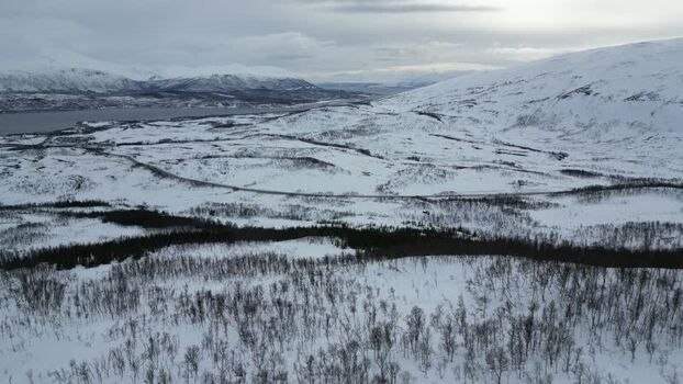 Aerial view of snowy mountains and fjord on Kvaloya Norway.