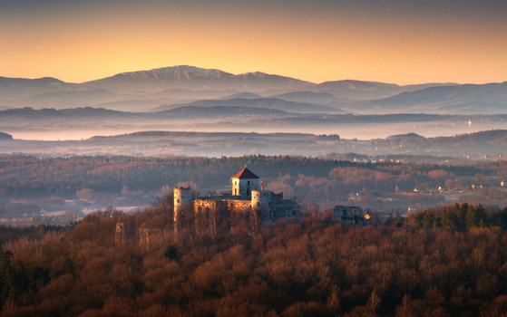 Aerial view of a medieval castle on a forested hill in the Krakow Czestochowa Upland with misty valleys and mountains at sunset Krakow County Lesser Poland Voivodeship Poland. Aerial view of a medieval castle on a forested hill in the Krakow Czestochowa Upland with misty valleys and mountains at sunset Krakow County Lesser Poland Voivodeship Poland.