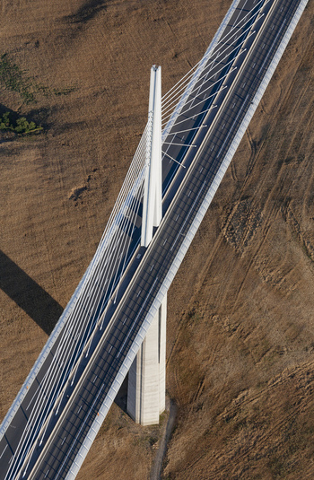 Aerial view of the Millau Viaduct soaring over the scorched landscape its stark white pillars contrasting with the golden fields below Millau France. Aerial view of the Millau Viaduct soaring over the scorched landscape its stark white pillars contrasting with the golden fields below Millau France.