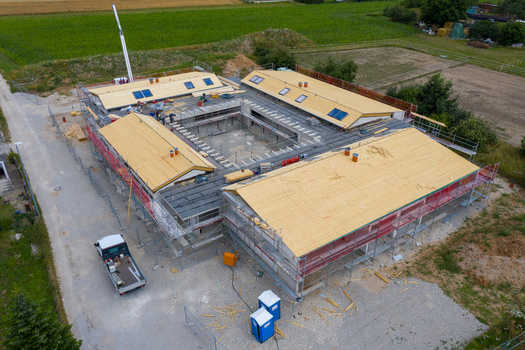 Igensdorf Germany 11 May 2024 Aerial view of a residential building under construction with wooden roof panels and scaffolding surrounded by green fields. Igensdorf Germany 11 May 2024 Aerial view of a residential building under construction with wooden roof panels and scaffolding surrounded by green fields.