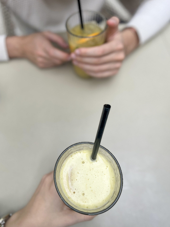 View of two people holding glasses of fresh fruit juice with black straws on a light colored table Beylikduzu Istanbul Turkiye. View of two people holding glasses of fresh fruit juice with black straws on a light colored table Beylikduzu Istanbul Turkiye.