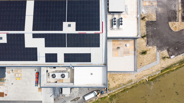 Aerial view of a modern logistics warehouse for fresh fruit and vegetable distribution featuring rooftop solar panels ventilation and cooling systems in Melegnano Lombardy Italy.