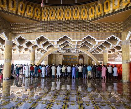 Tangail Bangladesh 21 March 2021 View of a large congregation of men praying their reflections shimmering on the polished floor beneath ornate golden architecture. Tangail Bangladesh 21 March 2021 View of a large congregation of men praying their reflections shimmering on the polished floor beneath ornate golden architecture.