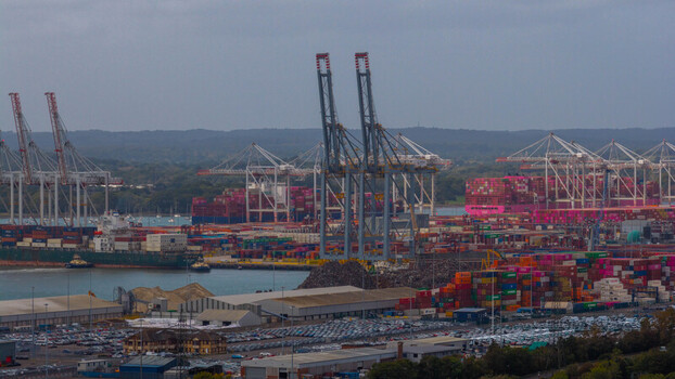 Aerial view of the busy Port of Southampton with large container ships towering gantry cranes colorful shipping containers and rows of parked vehicles in Southampton England United Kingdom. Aerial view of the busy Port of Southampton with large container ships towering gantry cranes colorful shipping containers and rows of parked vehicles in Southampton England United Kingdom.
