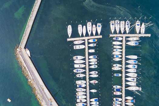 Aerial view of Sando marina with numerous sailboats moored at wooden piers in the clear blue water of the bay Vallda Hallands lan Sweden. Aerial view of Sando marina with numerous sailboats moored at wooden piers in the clear blue water of the bay Vallda Hallands lan Sweden.