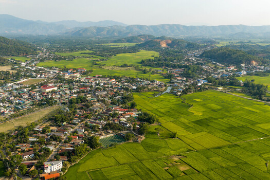 Aerial view of Lak Lake surrounded by lush green rice paddies small village houses and distant mountains in Lien Son Lak Dak Lak Vietnam. Aerial view of Lak Lake surrounded by lush green rice paddies small village houses and distant mountains in Lien Son Lak Dak Lak Vietnam.