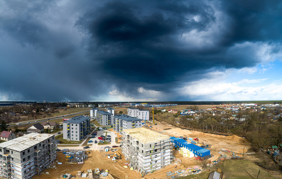 Aerial view of a construction site with multi story apartment buildings some under construction and others completed set against a dramatic dark stormy sky in Latvia. Aerial view of a construction site with multi story apartment buildings some under construction and others completed set against a dramatic dark stormy sky in Latvia.