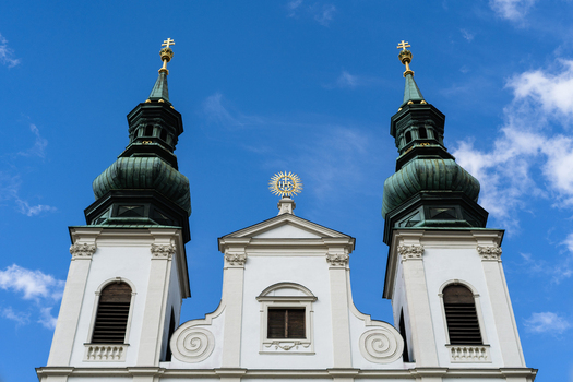 View of the Baroque facade and twin green domed towers of a historic church against a blue sky in Vienna Vienna Austria. View of the Baroque facade and twin green domed towers of a historic church against a blue sky in Vienna Vienna Austria.