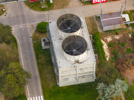 Aerial view of an industrial cooling tower with two large ventilation fans and surrounding infrastructure in Breclav South Moravian Region Czechia.