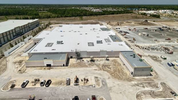 Aerial view of a large commercial building under construction with a white flat roof surrounding construction site and heavy machinery World Golf Village Florida United States.