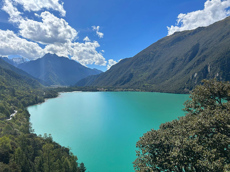 Aerial view of Batongtso Lake with its vibrant turquoise water surrounded by lush green mountains and dense forests under a bright blue sky in Xizang China. Aerial view of Batongtso Lake with its vibrant turquoise water surrounded by lush green mountains and dense forests under a bright blue sky in Xizang China.