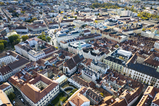 Aerial view of terracotta rooftops and sunlit facades create a warm mosaic contrasting with the shadowy courtyards below Graz Styria Austria.