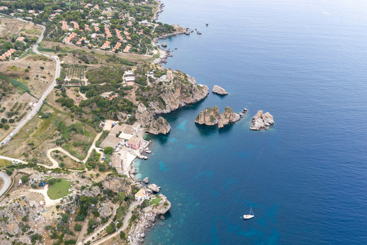 Aerial view of Riserva Naturale Orientata dello Zingaro with rocky cliffs turquoise sea and a small boat near the coast in San Vito Lo Capo Sicilia Italy. Aerial view of Riserva Naturale Orientata dello Zingaro with rocky cliffs turquoise sea and a small boat near the coast in San Vito Lo Capo Sicilia Italy.