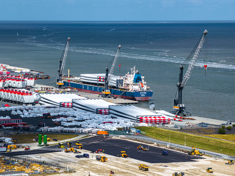 Aerial view of the Siemens Gamesa Renewable Energy facility with cargo ships loading wind turbine blades and heavy cranes at the port in Cuxhaven Niedersachsen Germany. Aerial view of the Siemens Gamesa Renewable Energy facility with cargo ships loading wind turbine blades and heavy cranes at the port in Cuxhaven Niedersachsen Germany.