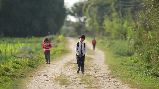 View of a schoolboy walking on a rural dirt road Nepal.