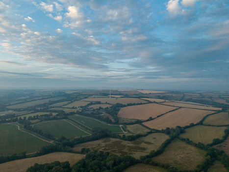 Aerial view of the misty rural countryside with agricultural farmland hedgerows and country roads under a soft morning sky in Looe Cornwall United Kingdom. Aerial view of the misty rural countryside with agricultural farmland hedgerows and country roads under a soft morning sky in Looe Cornwall United Kingdom.