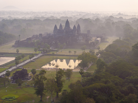 Aerial view of Angkor Wat temple complex emerging from morning mist surrounded by lush jungle and reflecting pools Krong Siem Reap Siem Reap Province Cambodia. Aerial view of Angkor Wat temple complex emerging from morning mist surrounded by lush jungle and reflecting pools Krong Siem Reap Siem Reap Province Cambodia.
