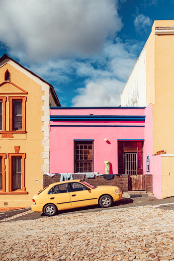 View of colorful houses and a yellow car parked on a steep cobblestone street in the Bo Kaap neighborhood Cape Town Western Cape South Africa. View of colorful houses and a yellow car parked on a steep cobblestone street in the Bo Kaap neighborhood Cape Town Western Cape South Africa.