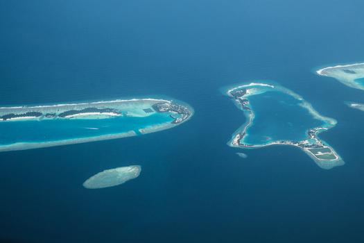 Aerial view of turquoise waters embrace the scattered islands and atolls like jewels in the vast expanse of the Indian Ocean Flight from Male to Hanimaadhoo island Maldives.