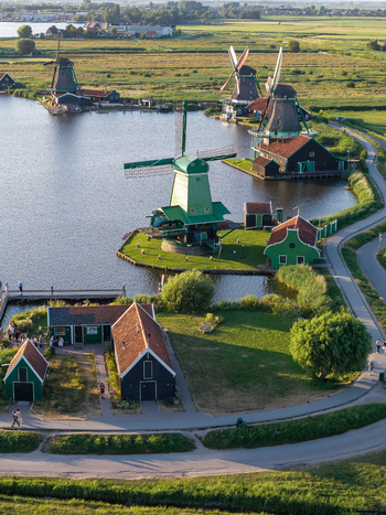 Aerial view of Zaanse Schans Windmill surrounded by traditional green wooden houses canals and lush green fields in Zaandam Noord Holland Netherlands.