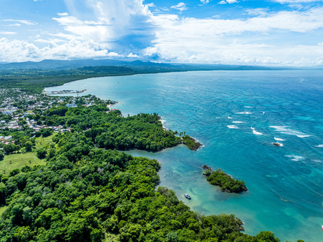 Aerial view of the coastline of Rio San Juan featuring lush vegetation turquoise waters small islets and a boat in a calm bay. Rio San Juan Maria Trinidad Sanchez Dominican Republic. Aerial view of the coastline of Rio San Juan featuring lush vegetation turquoise waters small islets and a boat in a calm bay. Rio San Juan Maria Trinidad Sanchez Dominican Republic.