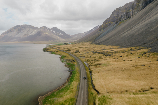 Aerial view of the winding road along the Stokksnes coastline with dramatic mountains and grassy plains Iceland.