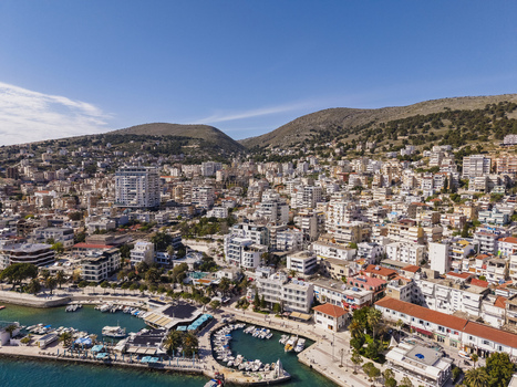 Aerial view of the coastal city of Saranda with its harbor dense urban architecture and surrounding hills under a clear blue sky in Saranda Vlore County Albania. Aerial view of the coastal city of Saranda with its harbor dense urban architecture and surrounding hills under a clear blue sky in Saranda Vlore County Albania.