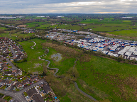 Aerial view of Doxey Marshes with its winding river and surrounding green fields adjacent to a large logistics depot and residential area in Stafford England United Kingdom. Aerial view of Doxey Marshes with its winding river and surrounding green fields adjacent to a large logistics depot and residential area in Stafford England United Kingdom.