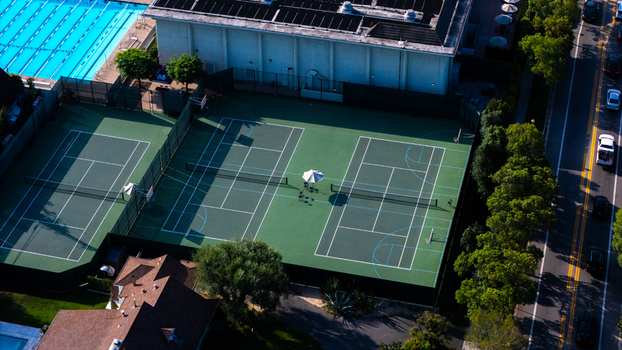 Aerial view of the tennis courts and swimming pool at Marlborough School surrounded by trees and adjacent to a road in Los Angeles California United States.