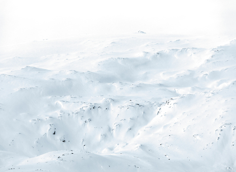View of a vast snow covered mountain slope with undulating drifts and ridges under a bright overcast sky in Tromso Troms Norway. View of a vast snow covered mountain slope with undulating drifts and ridges under a bright overcast sky in Tromso Troms Norway.