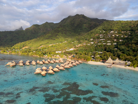 Aerial view of Sofitel Kia Ora Moorea Beach Resort with overwater bungalows in a turquoise lagoon lush mountains and sandy beach in Moorea Maiao Windward Islands French Polynesia. Aerial view of Sofitel Kia Ora Moorea Beach Resort with overwater bungalows in a turquoise lagoon lush mountains and sandy beach in Moorea Maiao Windward Islands French Polynesia.