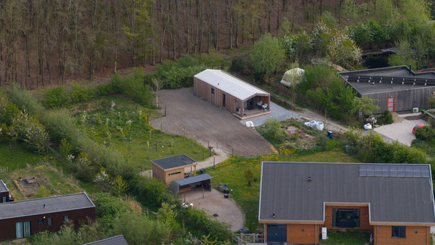 Aerial view of Ecodorp Bolderburen featuring modern sustainable wooden houses with solar panels and lush green gardens in Almere Flevoland Netherlands. Aerial view of Ecodorp Bolderburen featuring modern sustainable wooden houses with solar panels and lush green gardens in Almere Flevoland Netherlands.