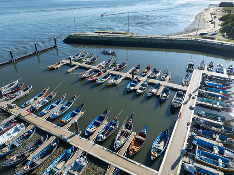 Aerial view of fishing boats neatly docked in the marina at Porta de Abrigo da Torreira where the sun kisses the water Aveiro Portugal.