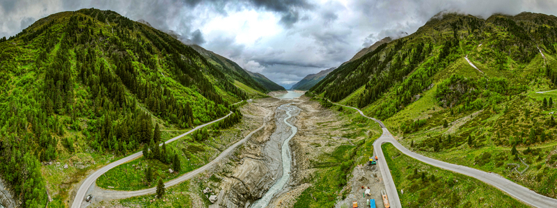 Aerial view of the winding mountain road and river flowing through the lush green valley in Prutz Tyrol Austria. Aerial view of the winding mountain road and river flowing through the lush green valley in Prutz Tyrol Austria.