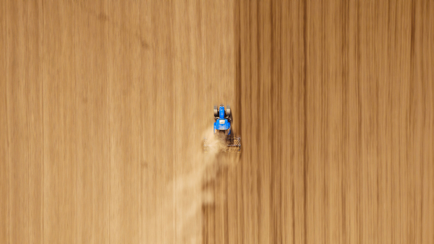 Aerial view of a lone blue tractor carving furrows in the vast ochre earth dust billowing behind like an earthbound cloud Sremska Mitrovica Vojvodina Serbia. Aerial view of a lone blue tractor carving furrows in the vast ochre earth dust billowing behind like an earthbound cloud Sremska Mitrovica Vojvodina Serbia.