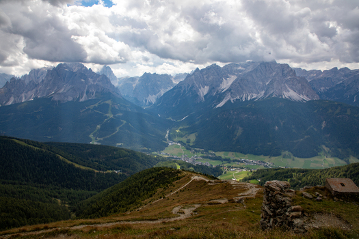 View of the majestic Dolomites mountain range with jagged peaks overlooking a lush green valley and a small alpine village under a dramatic cloudy sky Rocca Pietore Veneto Italy. View of the majestic Dolomites mountain range with jagged peaks overlooking a lush green valley and a small alpine village under a dramatic cloudy sky Rocca Pietore Veneto Italy.