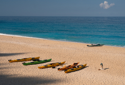 View of kayaks resting on the sandy shore where the turquoise sea meets the beach under a clear sky creating a scene of tranquility Lefkada Greece. View of kayaks resting on the sandy shore where the turquoise sea meets the beach under a clear sky creating a scene of tranquility Lefkada Greece.