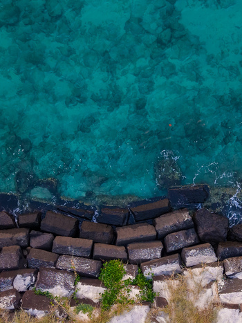 Aerial view of the stone breakwater at Cudgen Creek meeting the clear turquoise water of the ocean in Tweed Shire Council New South Wales Australia.