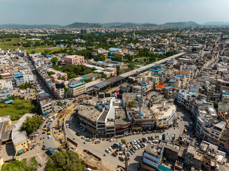 Aerial view of a busy urban intersection with dense buildings traffic and road infrastructure in Udaipur Rajasthan India.