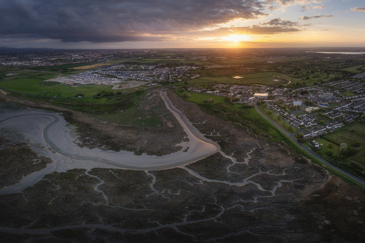Aerial view of winding estuary channels and residential neighborhoods under a dramatic sunset sky in Portmarnock County Dublin Ireland. Aerial view of winding estuary channels and residential neighborhoods under a dramatic sunset sky in Portmarnock County Dublin Ireland.