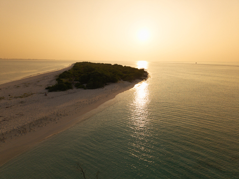 Aerial view of Kan island touched by the golden hues of the setting sun where the turquoise sea meets the pristine white shores Dhidhdhoo Thiladhunmathi Atoll Maldives.