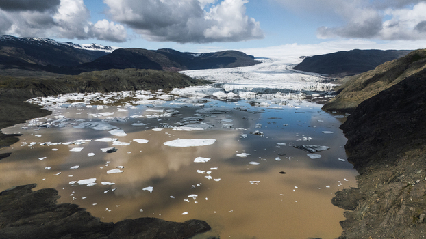 Aerial view of glacial ice drifts serenely on the murky waters framed by rugged mountains under a textured sky Hoffellsjokull Iceland. Aerial view of glacial ice drifts serenely on the murky waters framed by rugged mountains under a textured sky Hoffellsjokull Iceland.