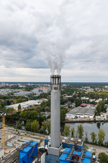 Aerial view of Klarwerk Ruhleben sewage treatment plant with a tall chimney emitting steam surrounded by industrial buildings trees and the river Spree in Berlin Berlin Germany.