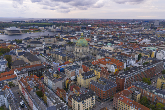 Aerial view of Frederik s Church with its iconic green dome surrounded by historic rooftops and the city skyline under a cloudy sky in Copenhagen Denmark. Aerial view of Frederik s Church with its iconic green dome surrounded by historic rooftops and the city skyline under a cloudy sky in Copenhagen Denmark.