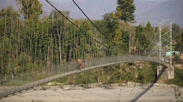 View of a long suspension bridge over a riverbed in Surkhet Nepal.