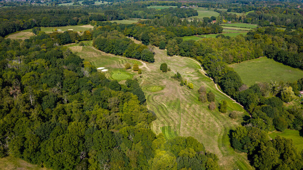 Aerial view of Hamptworth Golf course featuring lush green fairways sand bunkers and surrounding dense woodland under a clear sky in Hamptworth England United Kingdom. Aerial view of Hamptworth Golf course featuring lush green fairways sand bunkers and surrounding dense woodland under a clear sky in Hamptworth England United Kingdom.