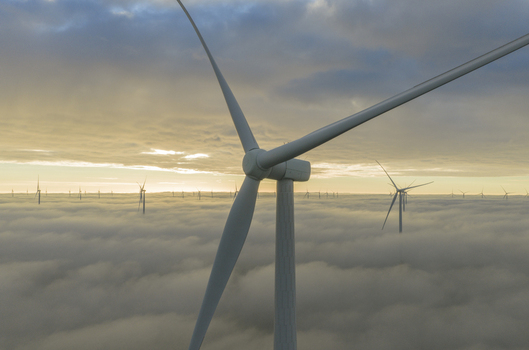 Aerial view of wind turbines rising above a thick layer of clouds during a golden sunrise in Netherlands. Aerial view of wind turbines rising above a thick layer of clouds during a golden sunrise in Netherlands.