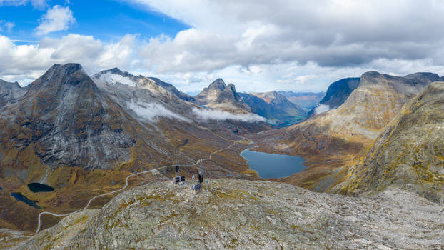 Aerial view of the dramatic mountain landscape near Trollstigen with a winding road a small lake and rocky peaks under a cloudy sky in Andalsnes More og Romsdal Norway.