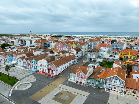 Aerial view of vibrant colorful houses stretching towards the beach under a cloudy sky Costa Nova Portugal.